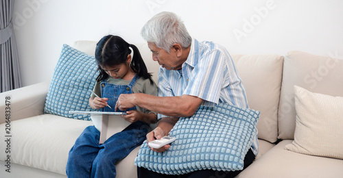 Quadro em tela Asian grandfather and granddaughter spending time together at home, sharing learning, family love, care, and meaningful intergenerational moments