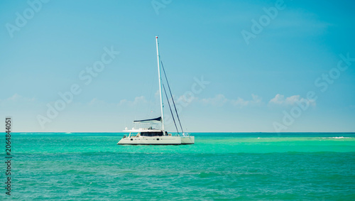 Modern catamaran sailboat anchored in turquoise tropical ocean waters.