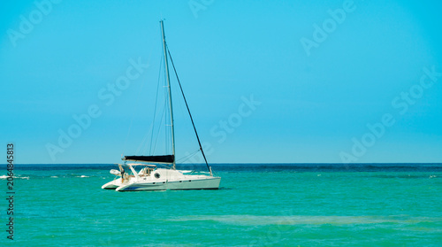 Modern catamaran sailboat anchored in turquoise tropical ocean waters.