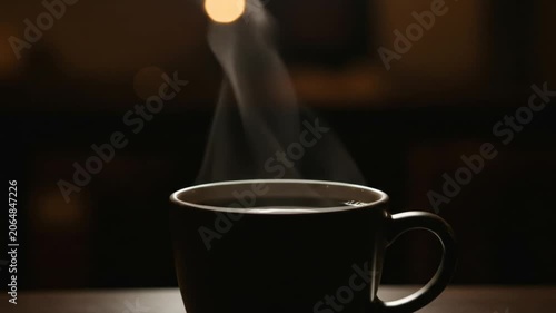 Steaming hot coffee in a dark mug with soft bokeh background.