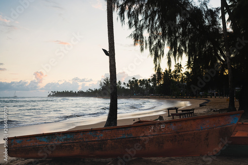 Traditional wooden fishing boats on a tropical beach at sunset.