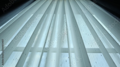 Close-up view of modern sheer curtain fabric with vertical pleated texture, illuminated by soft natural light. Minimalist interior design background featuring clean lines and geometric patterns