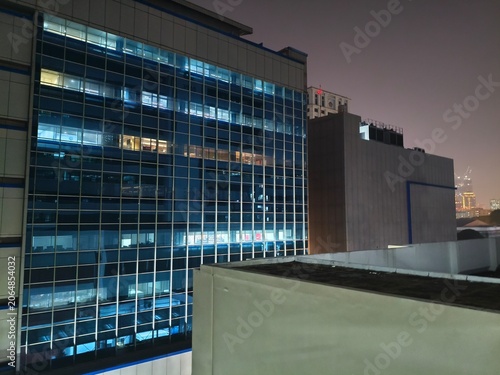 Modern Office Building at Night, Illuminated Windows, City Skyline Background