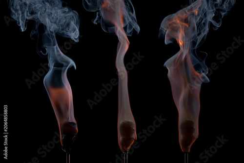 Foto Active torches with hot smoldering embers emitting dynamic wisps of smoke against a dark backdrop