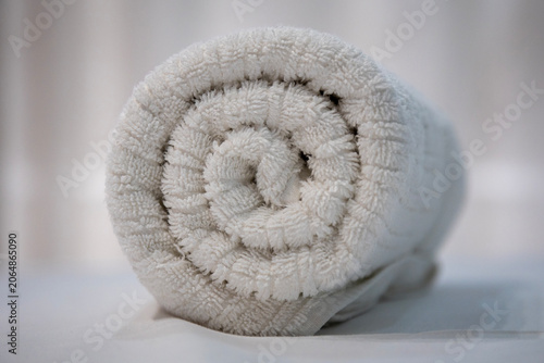 A towel seen from very close up, where an elegant fold is visible, giving it a circular shape. The texture of the white towel material is noticeable.
