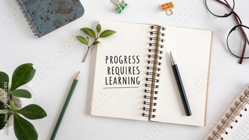 Inspirational quote in notebook surrounded by stationery and plants promoting growth and learning in workspace environment