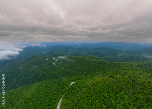 Drone perspective of lush green forests blanketed by drifting mist in the Blue Ridge Mountains, creating a serene and atmospheric landscape across the Appalachian highlands.