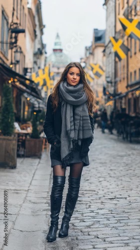 A fashionable woman strolls through a picturesque old town street, exuding confidence and elegance. The cozy atmosphere, trendy attire, and historic architecture create a modern city vibe