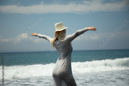 Fotografie Woman spreads arms wide while enjoying the ocean breeze