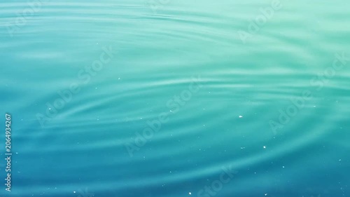 Gentle ripples expand across a calm turquoise water surface