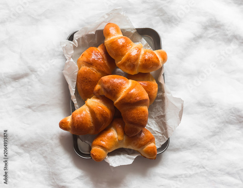 Homemade  croissants on a metal tray on light background, top view