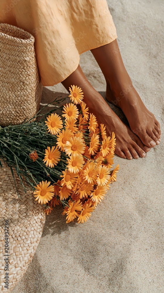 Obraz premium Close-up of bare feet beside orange flowers on textured surface