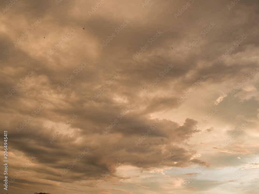 Obraz premium Sunset sky was beautiful, with thick, dark orange and golden clouds near the horizon and dark, warm-toned clouds turning cool blue at the bottom.