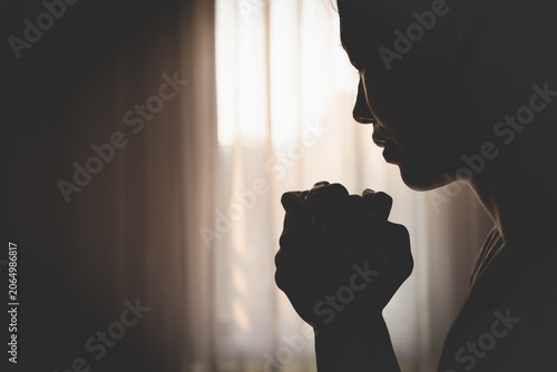 Canvas Print Woman praying in silhouette against dramatic light, conveying hope, belief, and religious devotion