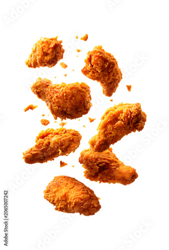 Multiple fried chicken pieces falling on checkered 