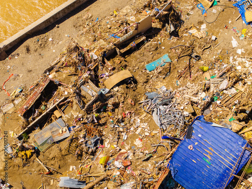 Talisay, Philippines - 11 November 2025: Aerial view of the devastating aftermath of a flood showing destroyed homes, scattered debris, and thick mud along a riverbank.