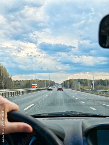 Woman drives solo on a road trip seen through the car windshield focusing on the journey ahead