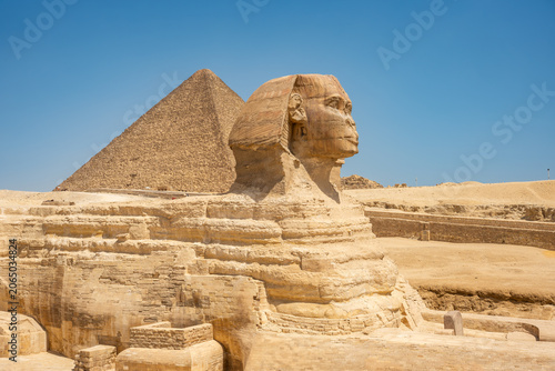 Fotografie The Great Sphinx of Giza and Khufu's Great Pyramid at the background, southwest of Cairo, in Egypt