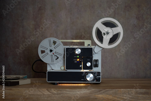 Vintage Super 8 Film Projector Centered on Wooden Table with Illuminated Controls