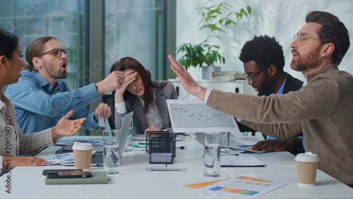 Fotografie Overworked exhausted business team leader boss woman suffer headache group of managers arguing with paperwork at office briefing