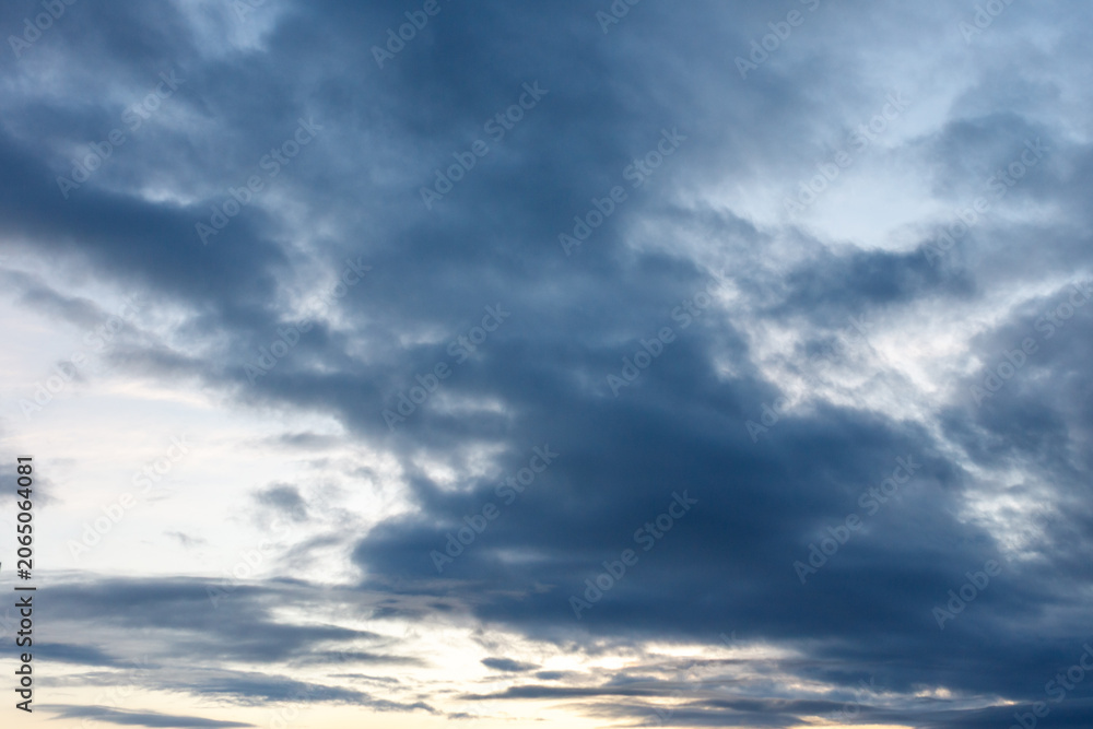 Fototapeta premium Overcast sky with deep blue clouds and golden light breaking through
