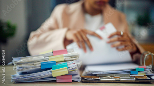 Obraz na plátne Woman reviews papers at cluttered desk