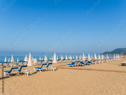Foto Beach loungers and umbrellas on a sandy shoreline