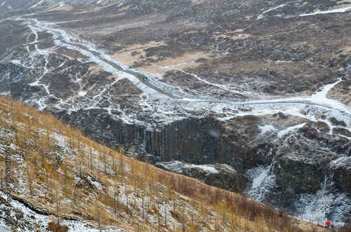 Hikers walking along a snowy path over dramatic basalt columns at Studlagil canyon , iceland. Travel destination, icelandic landscape nature reserve national park