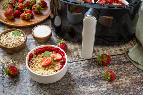Healthy cooking with air fryer: homemade dessert traditional English crumble cake with strawberry on a wooden table. Copy space.