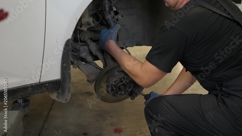 A close-up of a mechanic removes shock absorbers from a car that is lifted on a lift in an auto repair shop. Repair of shock absorbers in a modern service station.