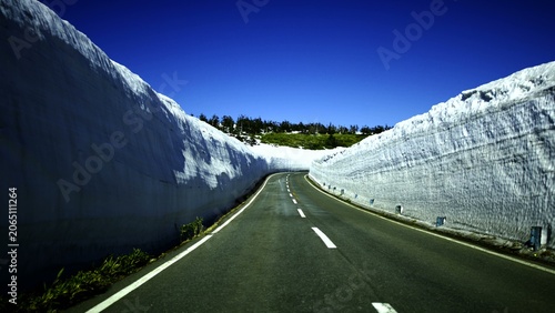 Canvas-taulu An asphalt road carves through massive banks of accumulated snow that tower on b