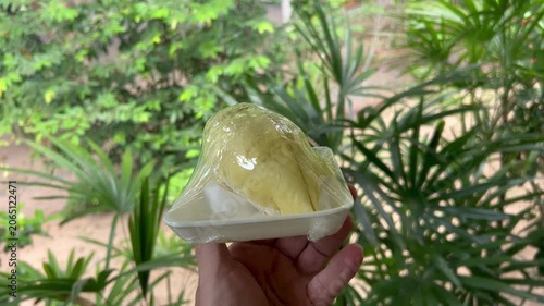 Man holds two pieces of durian on plate