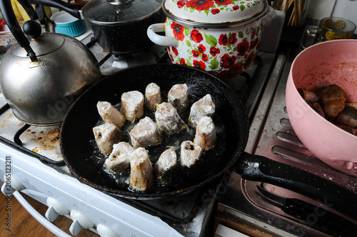 Fish pieces frying in a pan on a gas stove