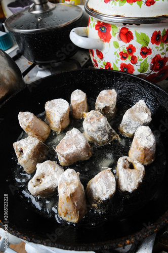 Fish pieces frying in a pan on a stove