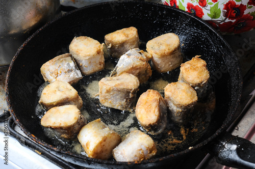 Fried fish pieces cooking in a hot pan with oil