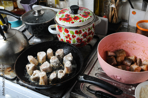 Fish frying in a pan on a messy kitchen stove