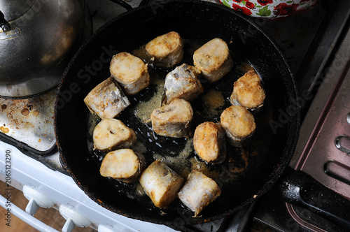 Fish pieces frying in a cast iron pan
