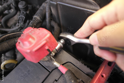 Φωτογραφία Hand using a ratchet wrench to loosen or tighten a bolt on a car battery termina