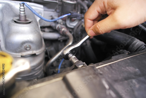 Obraz na plátne Hand using a socket ratchet wrench to loosen or tighten a bolt in a car engine b