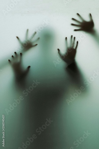 Tableau sur toile Multiple blurry hands pressing against frosted glass surface evoking deep overwh