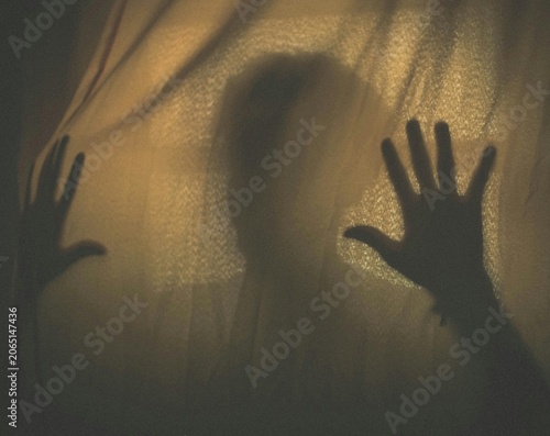 Mysterious blurry silhouette of hands pressing against textured fabric curtain evoking fear panic and deep psychological isolation