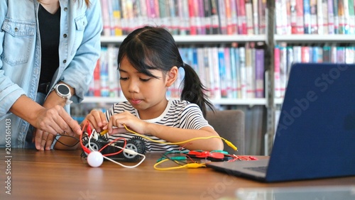 Photos Young Asian female child building STEM robotic car project improving smart mechanical coding logic