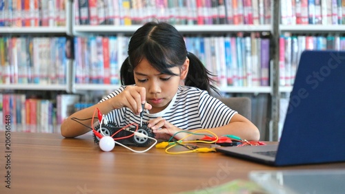 Clever Asian youth learner coding miniature electrical vehicular device to enhance creative problem solving. Designing miniature autonomous platforms creates supreme confidence.