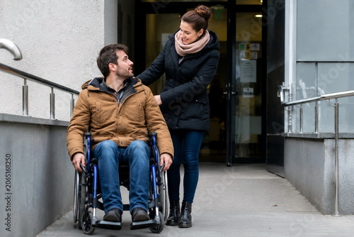 personne handicapée en fauteuil roulant  accompagnée par un aidant 