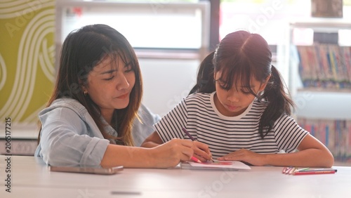 Fotografija Smart Asian kid student sharing textbook wisdom with classmate friend at library table
