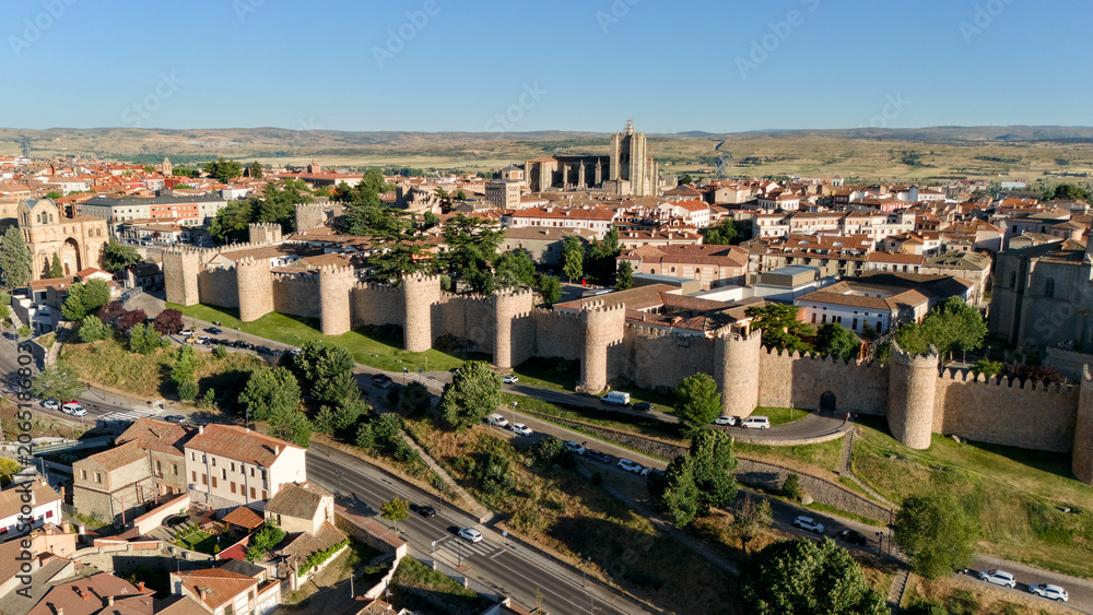 Obraz premium Drone view of Avila city walls long facade with multiple towers and tree lined boulevard in Spain