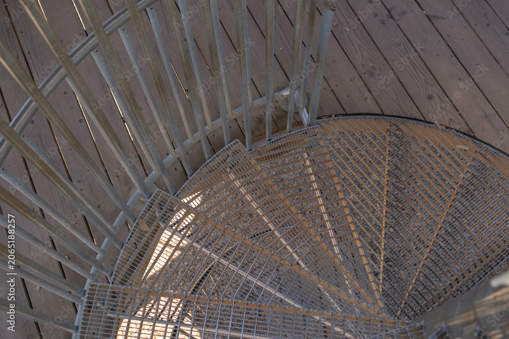 Obraz premium Top view of a metal spiral staircase entry. Architectural abstract of metal stair steps. Close up of outdoor metal spiral staircase