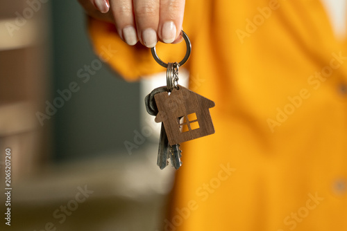 Fotografie Woman's hand holding a keyring with several house keys and a small wooden house