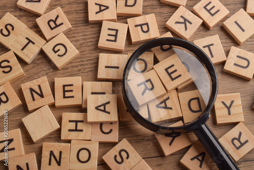 Bild auf Leinwand Word search concept with magnifying glass highlighting letter tiles on wooden background, symbolizing discovery, investigation, information search, learning, problem solving, and analysis