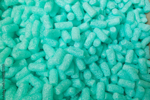 Close-up texture of turquoise packing peanuts. Abstract background for shipping, logistics, packaging and product protection concepts.